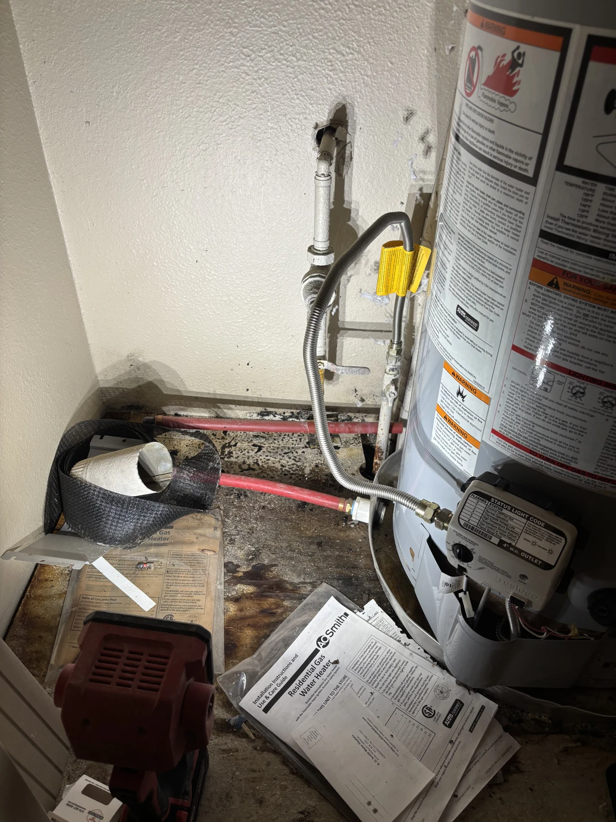 Existing water pressure regulator and water heater connections before replacement in a Fayetteville, Arkansas water-heater closet.