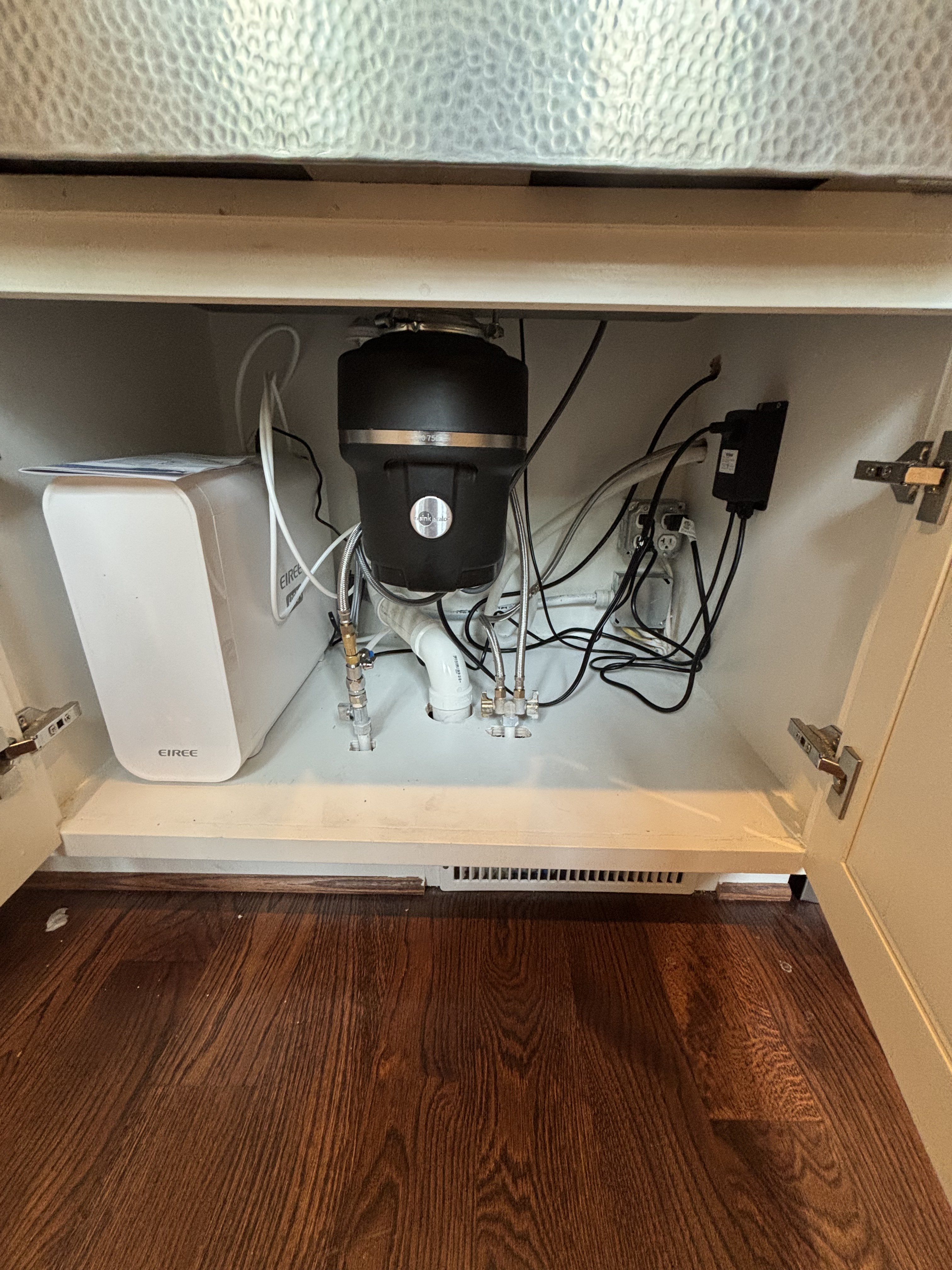 Completed InSinkErator garbage disposal installation by United Plumbing under a kitchen sink.