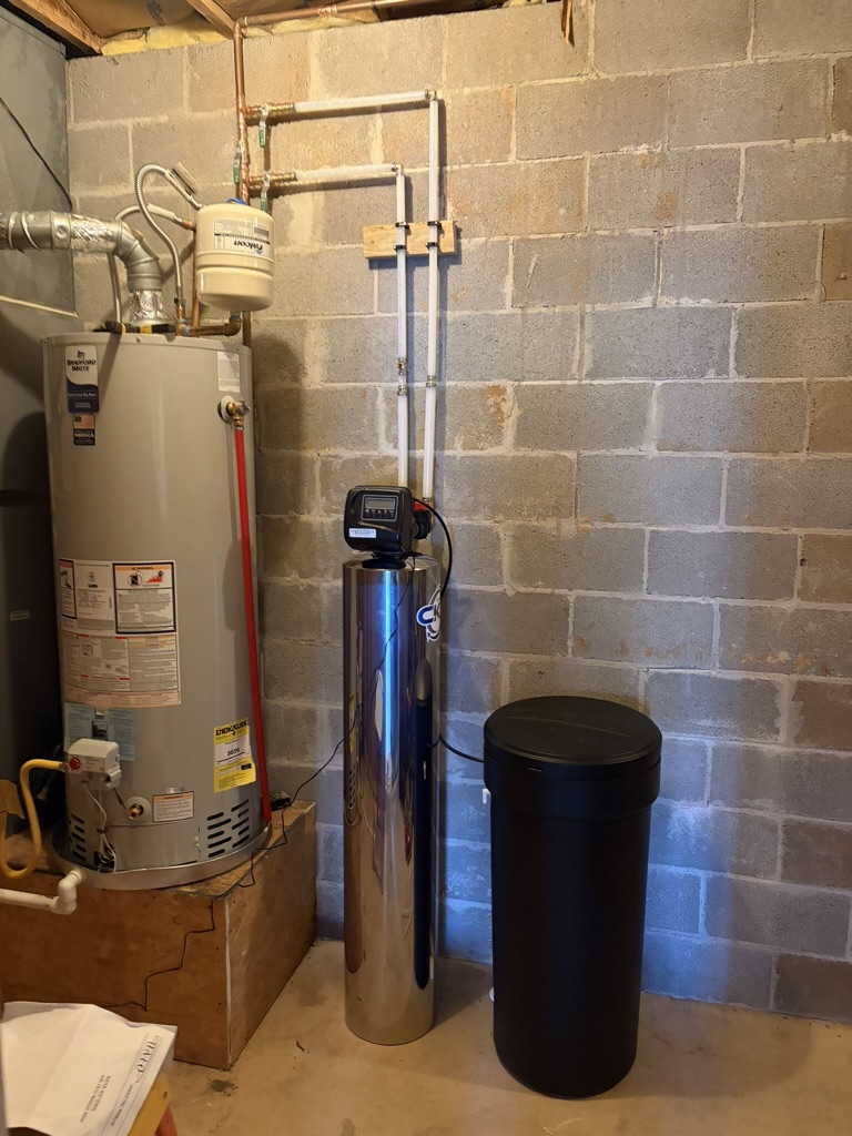 Completed whole-home filtration and softening equipment beside a new water heater in a Bentonville, Arkansas home.